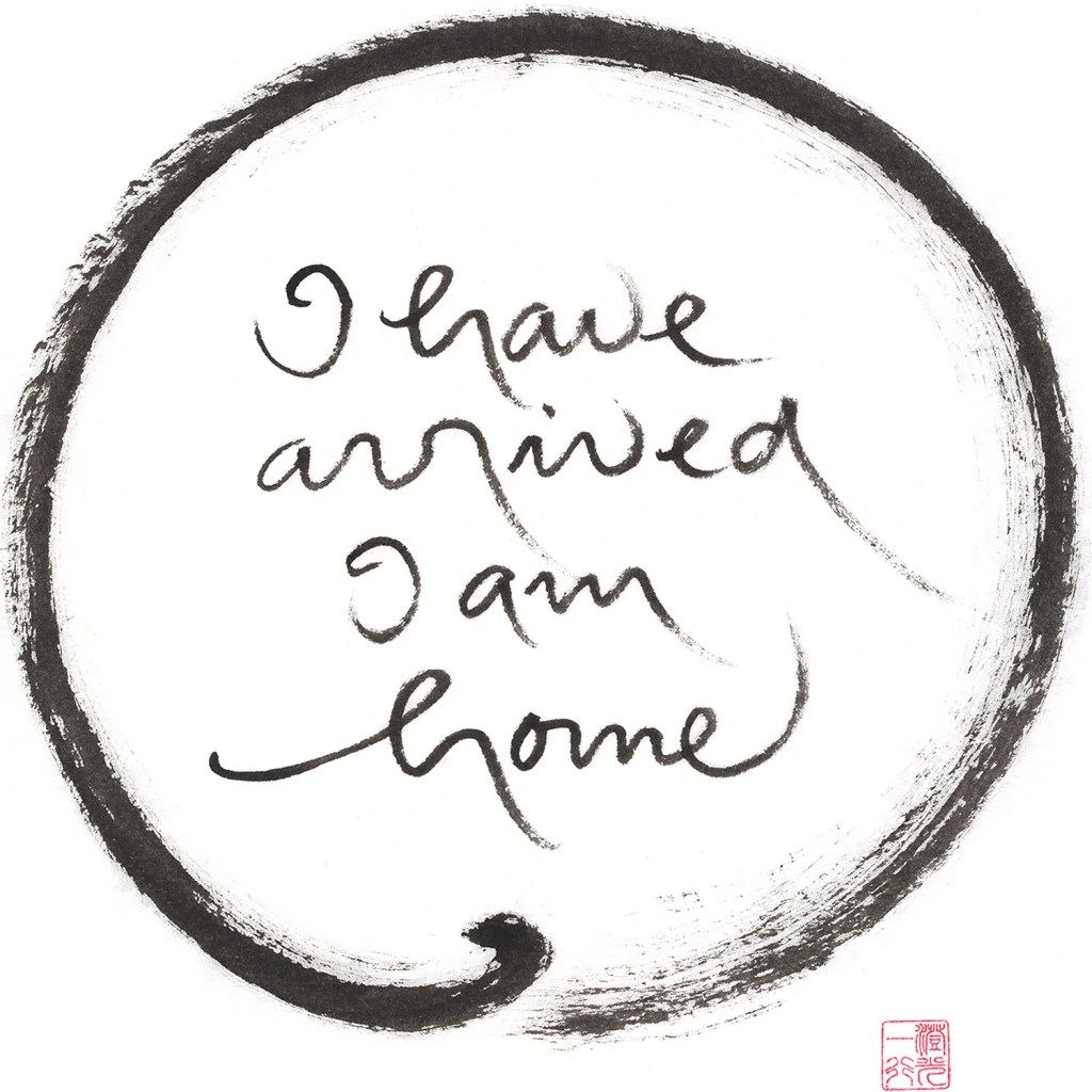Brush calligraphy saying "I have arrived I am home" surrounded by a circle, all in black ink, with a small block of red printing at the bottom right.